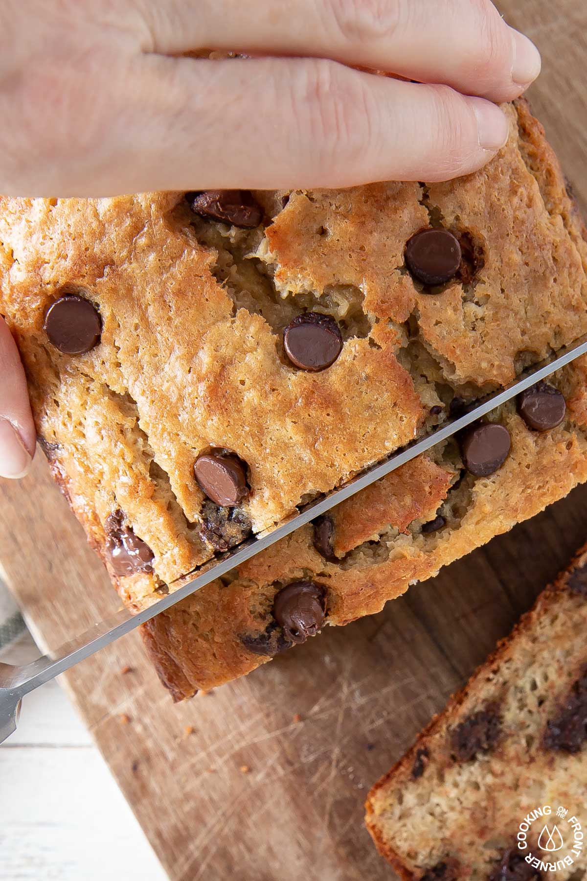 cutting a slice of banana bread from a loaf