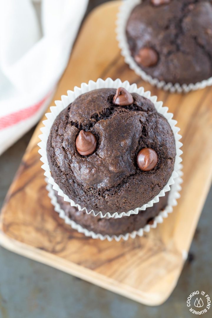 two chocolate chip banana muffins stacked on a cutting board