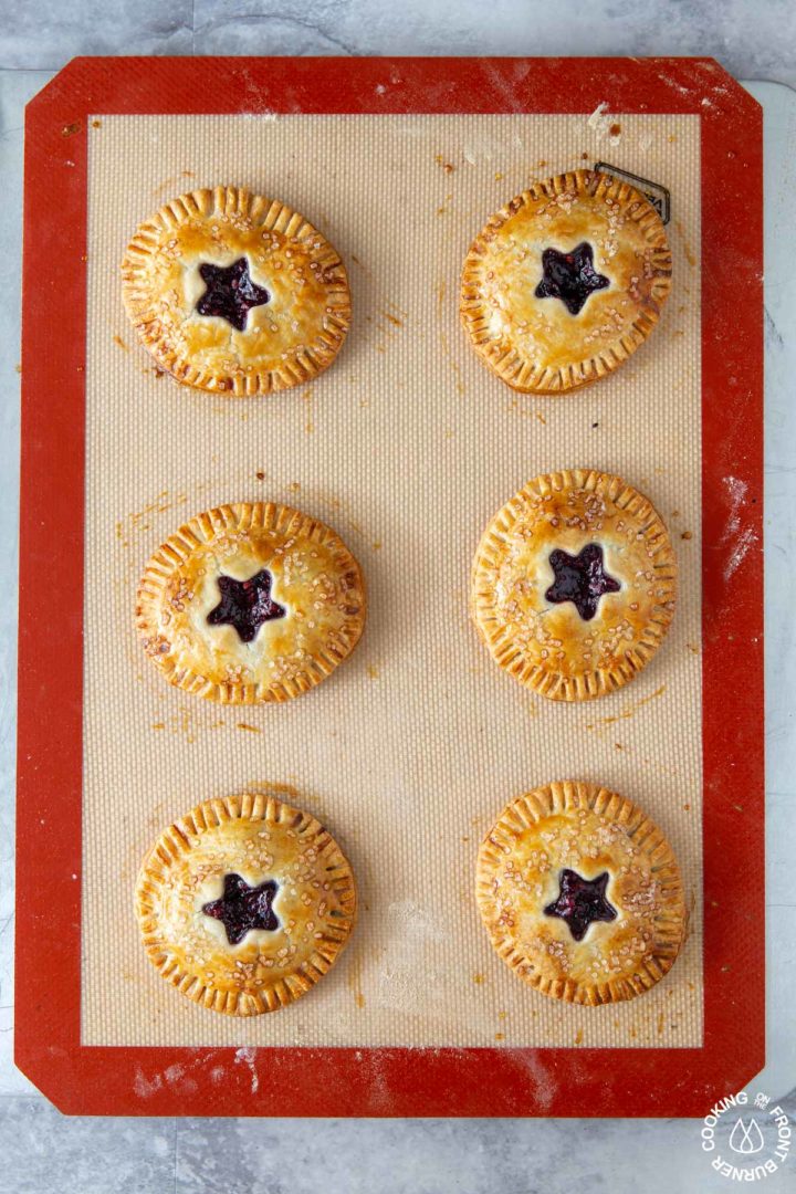 6 blackberry hand pies on a cookie sheet out of the oven - they are golden brown