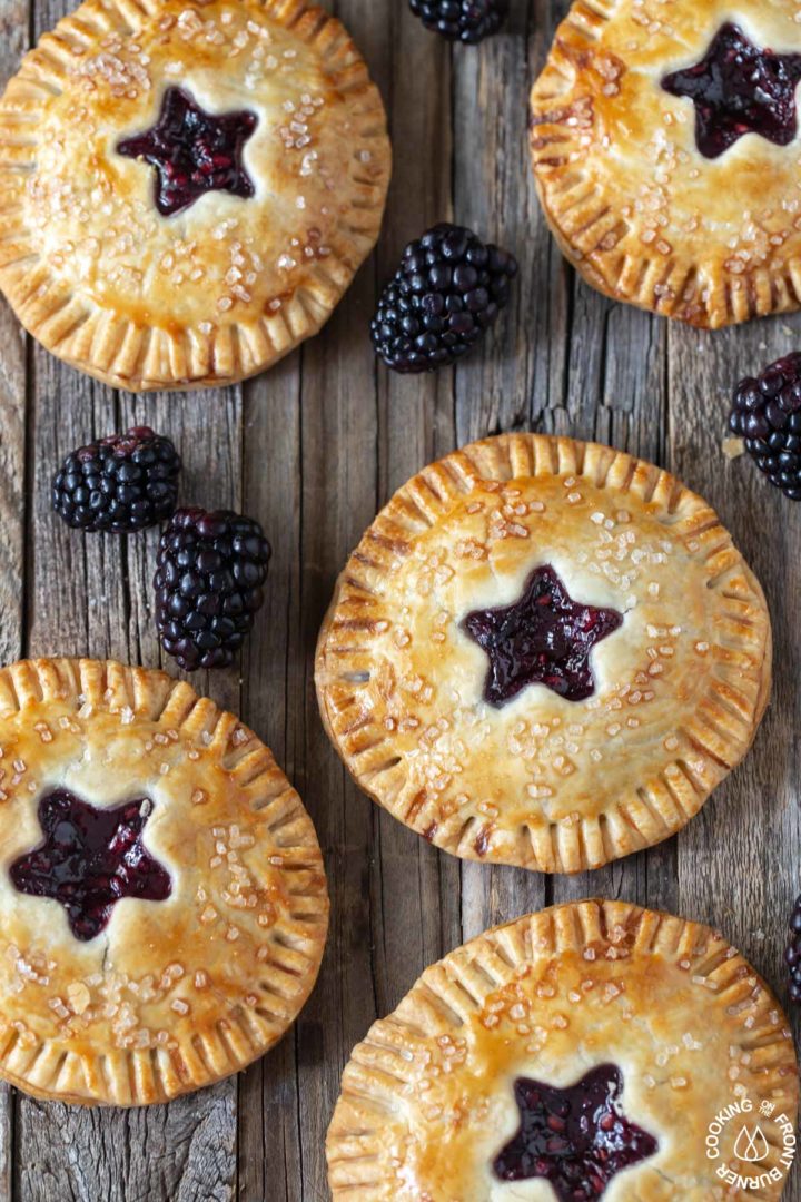 blackberry hand pies on a board with a few fresh blackberries around them