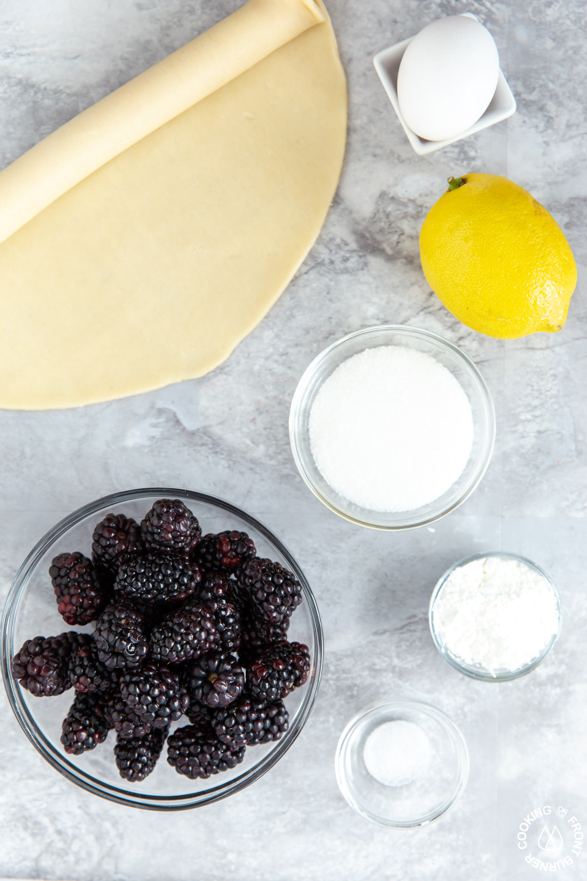 unbaked pie crust, sugar, cornstarch, salt, a lemon and fresh blackberries on a board