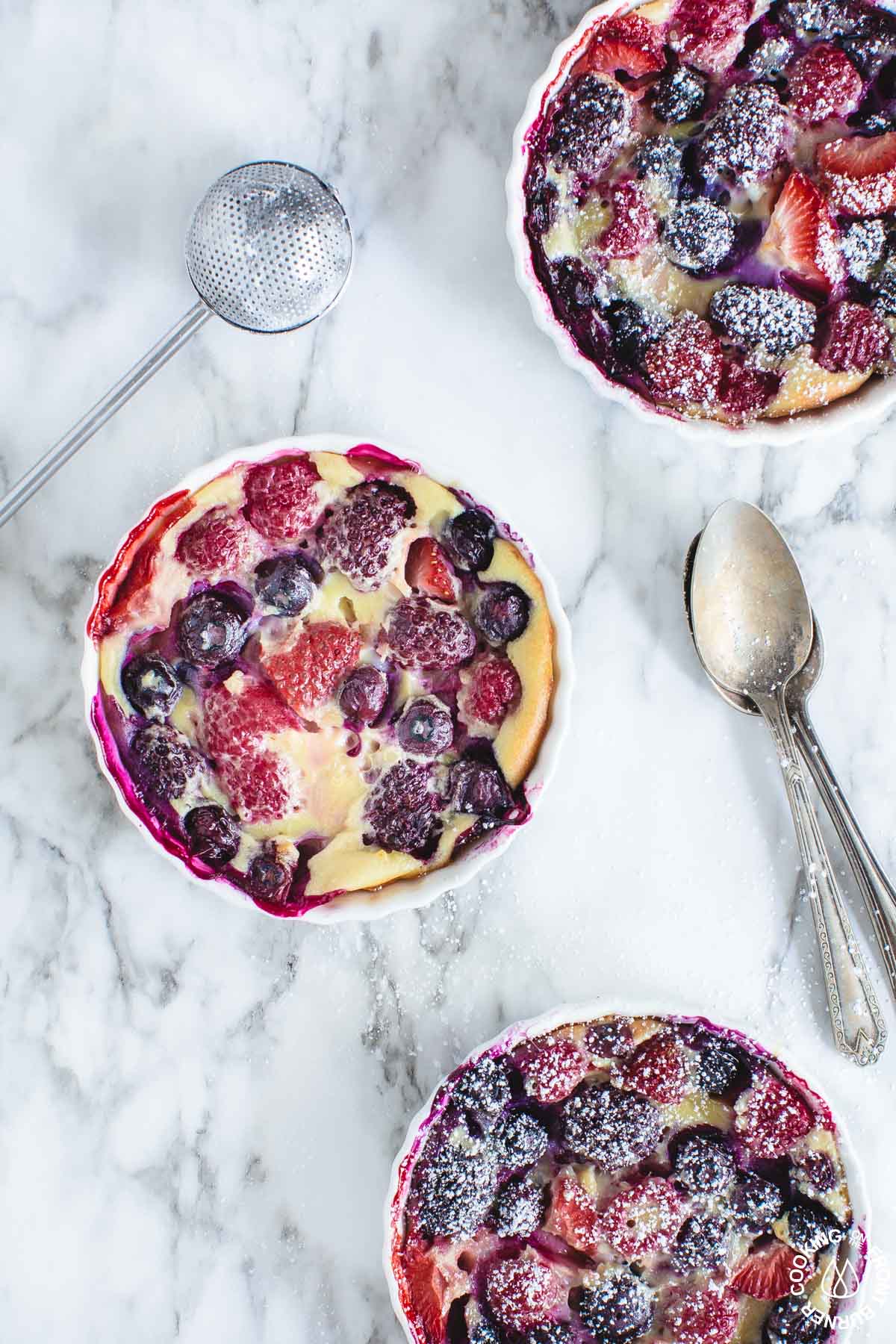 3 ramekins on a board with baked pudding cakes along with 2 spoons