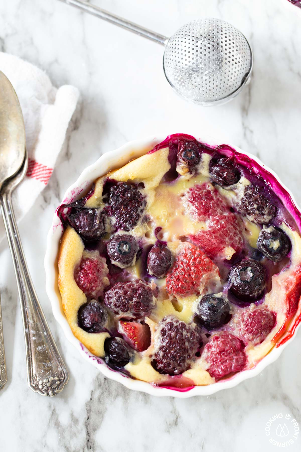 a close up shot of the mixed berry pudding cake with a spoon in it