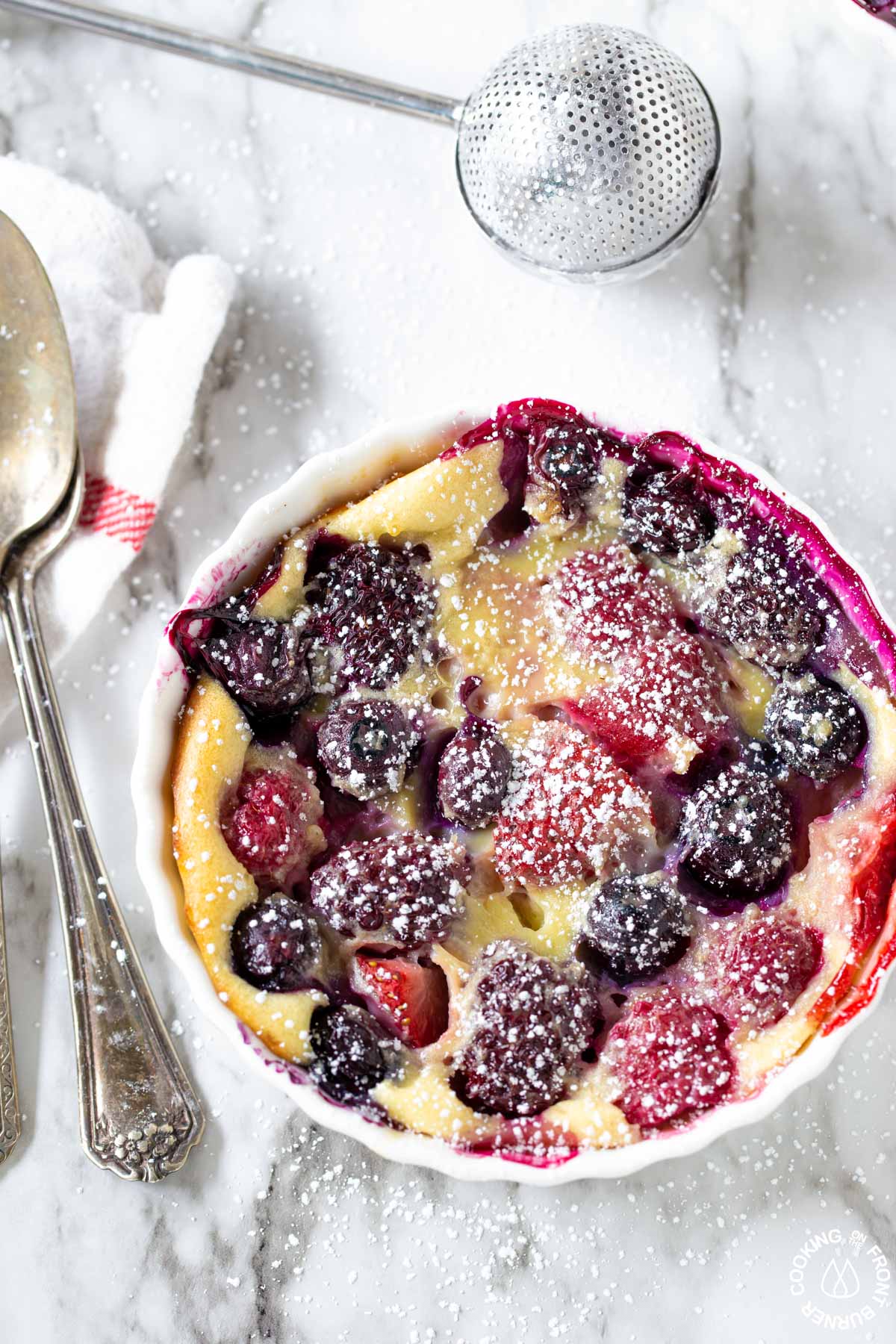 a close up shot of mixed berry pudding cake with powdered sugar on top