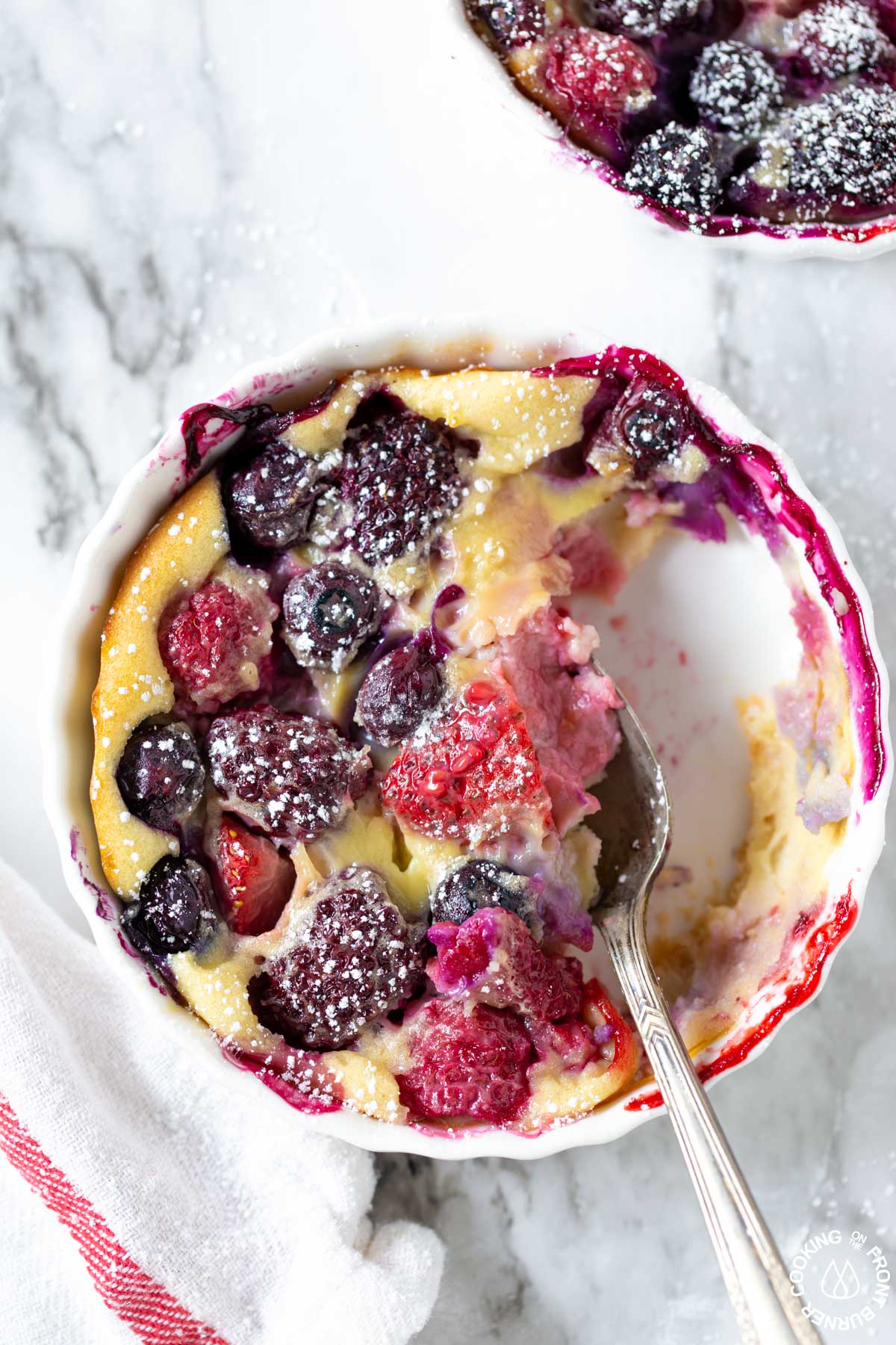 a berry tart with a spoon in the ramekin and a bit taken out