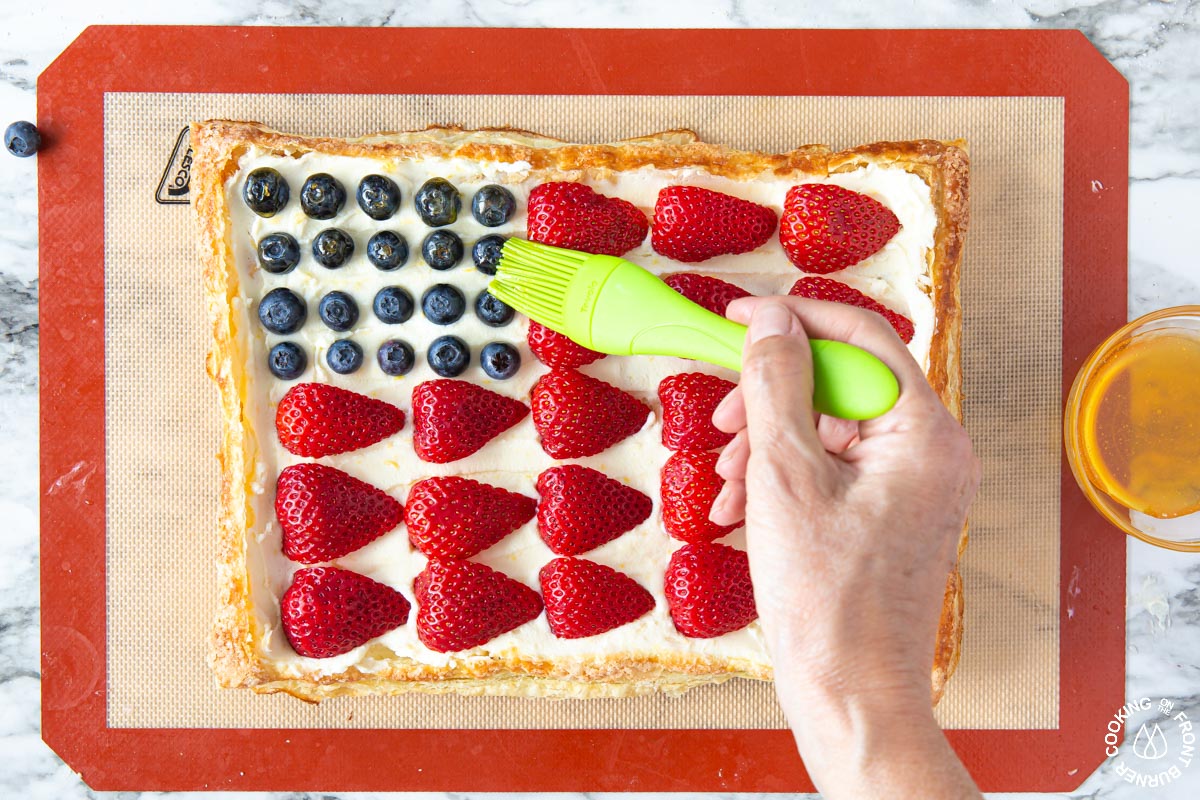 brushing a glaze of apricot jelly over fruit in a tart