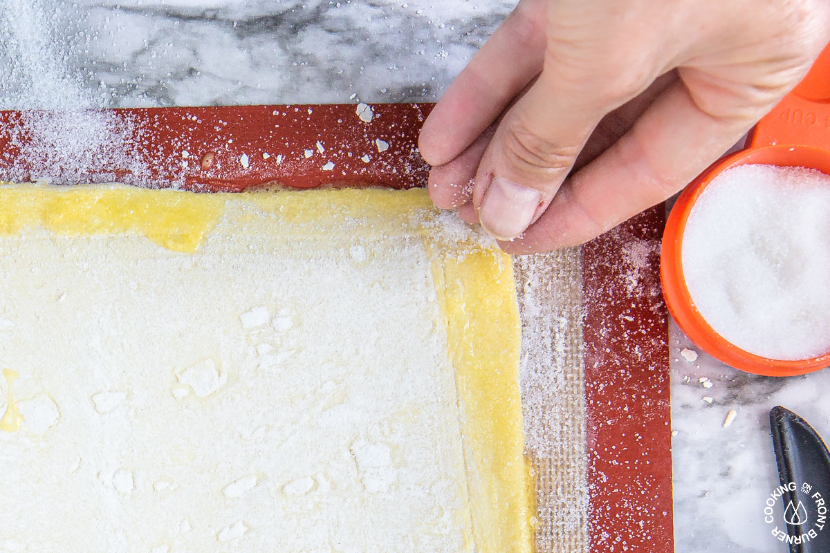 sprinkling sugar on puff pastry over an egg wash