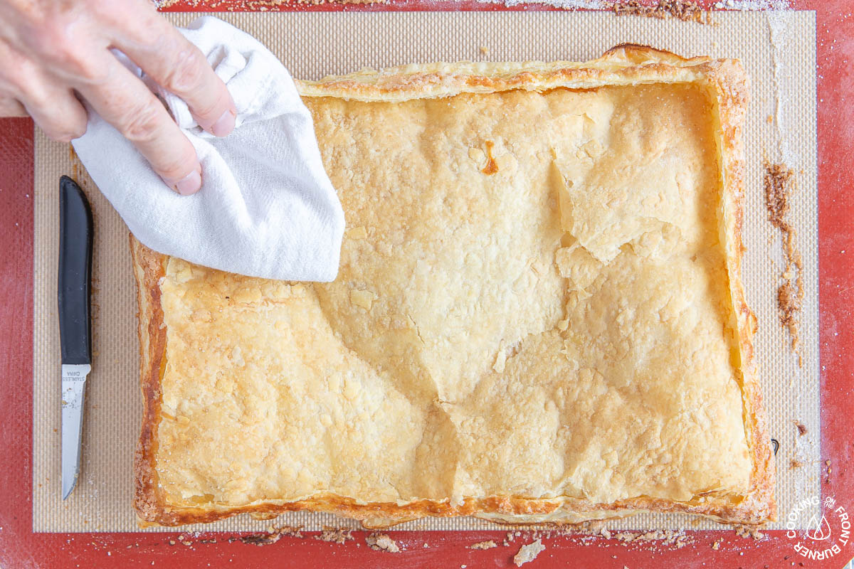 using a cloth to press down the center of a puff pastry tart