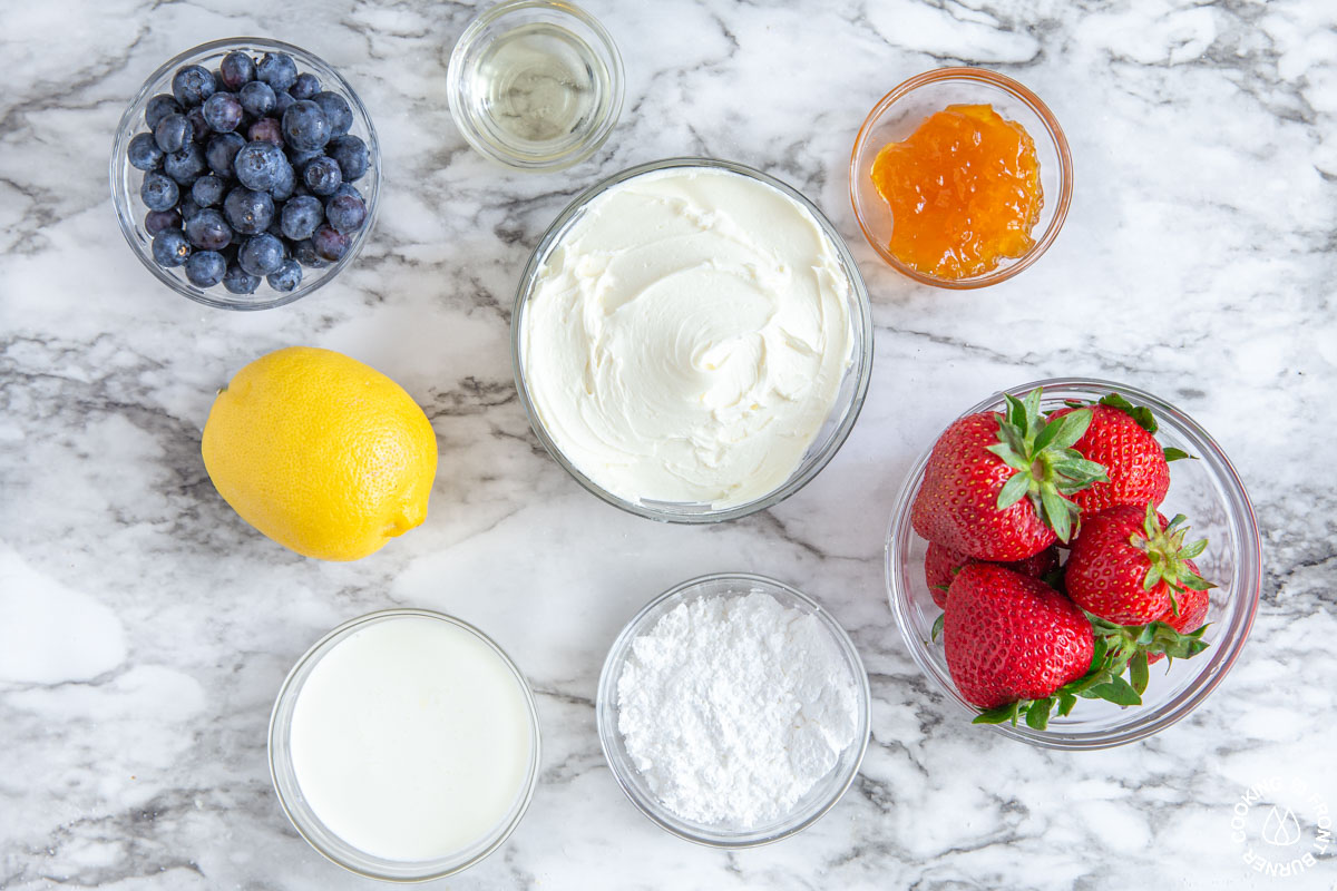 blueberries, strawberries, mascarpone cheese, lemon, heavy cream, powdered sugar, apricot jelly on a board measured in bowls