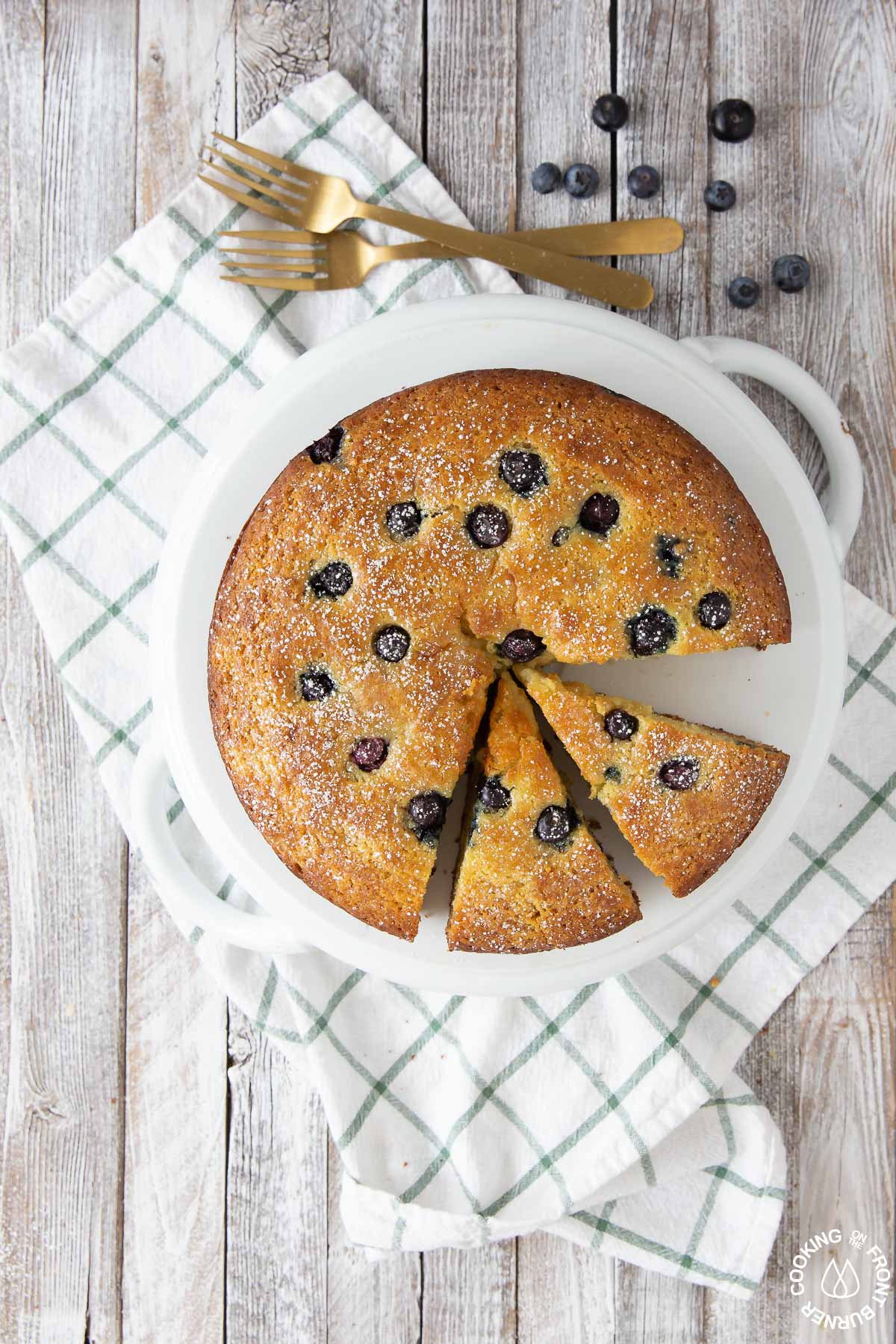a lemon blueberry ricotta cake on a plate with two slices cut into it