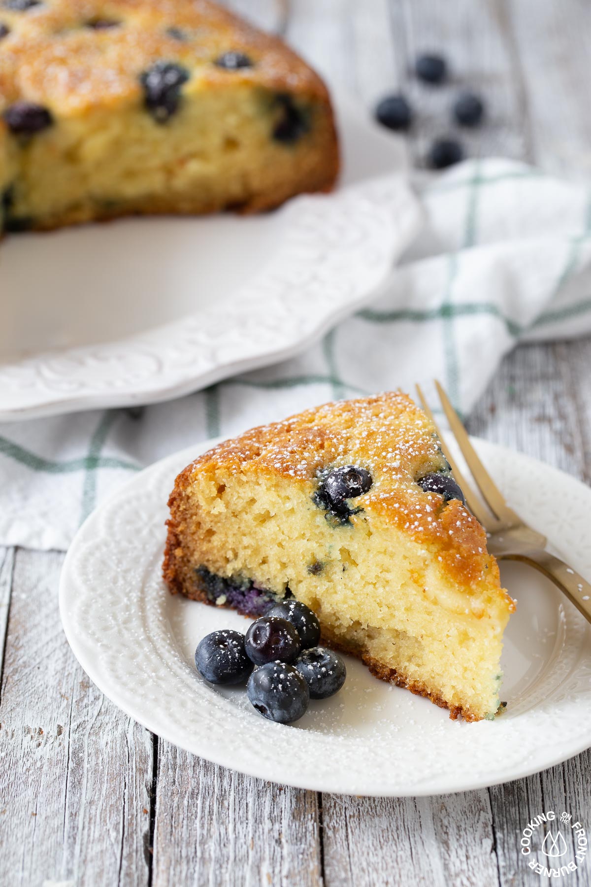 a slice of lemon blueberry ricotta cake on a plate with a fork next to it