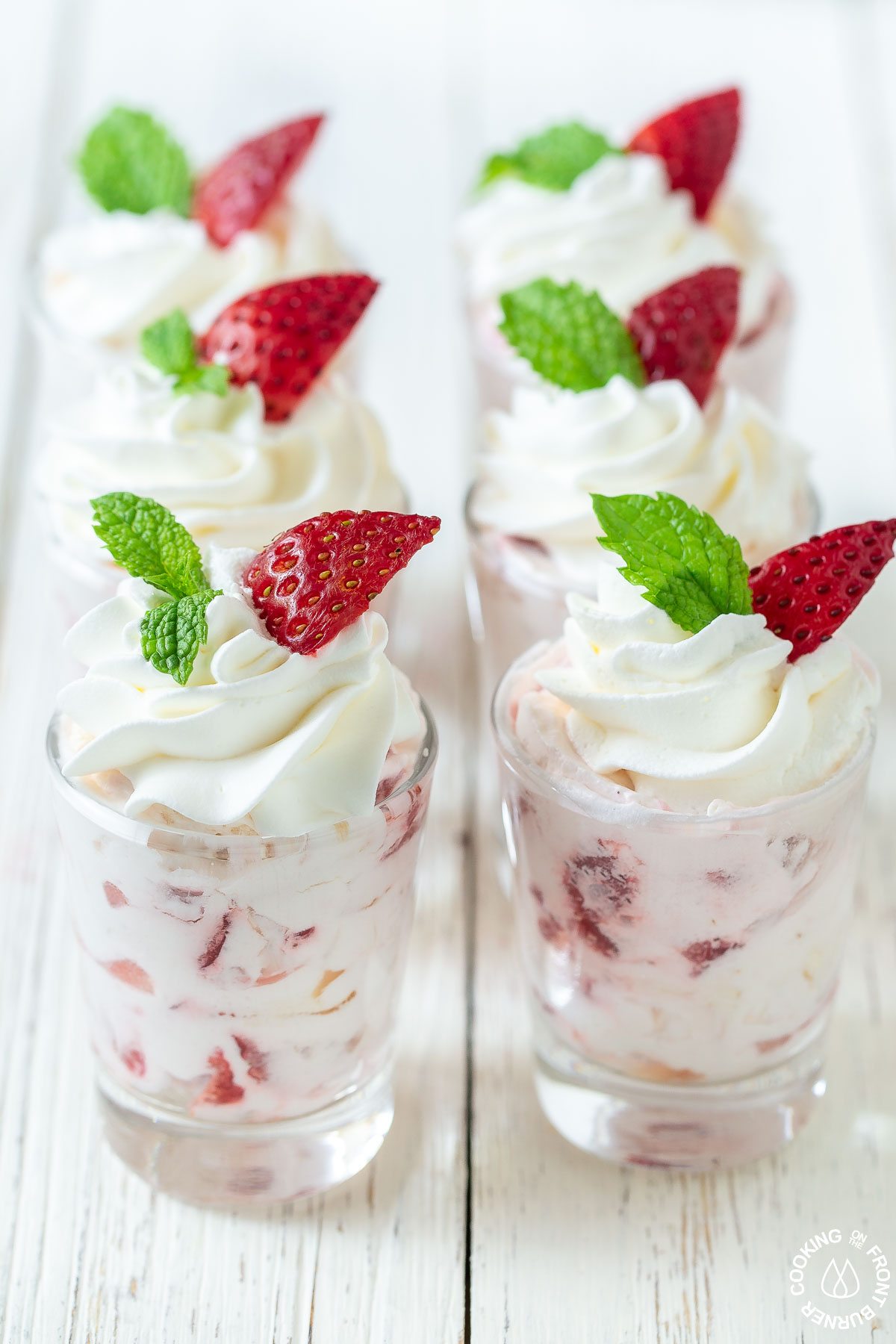 6 small shot glasses filled with strawberry filling and topped with cool whip and a mint leaf