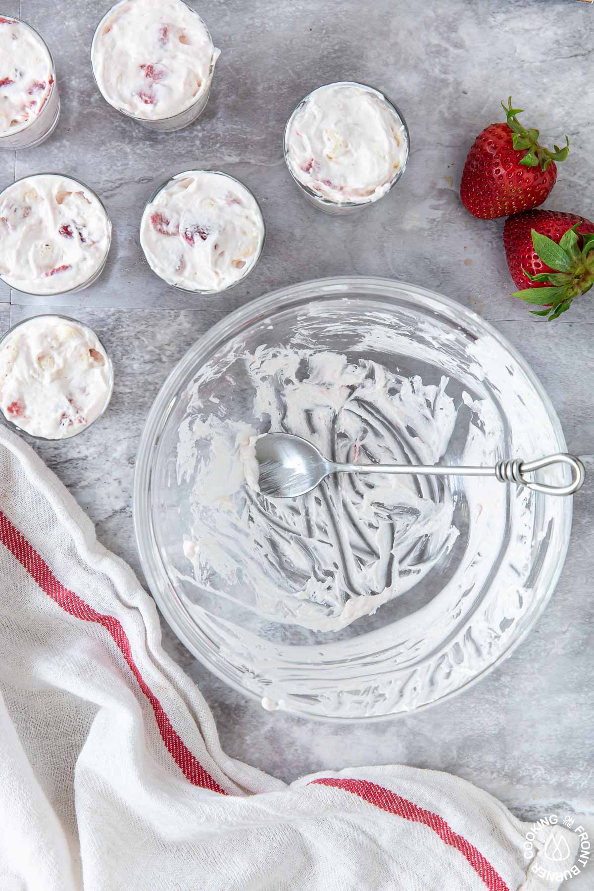 am empty bowl alongside small shot glasses with strawberry filling in them