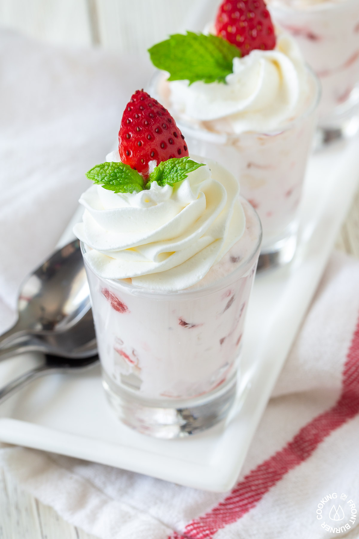 a small shot glass with strawberry whipped cream filling on a plate