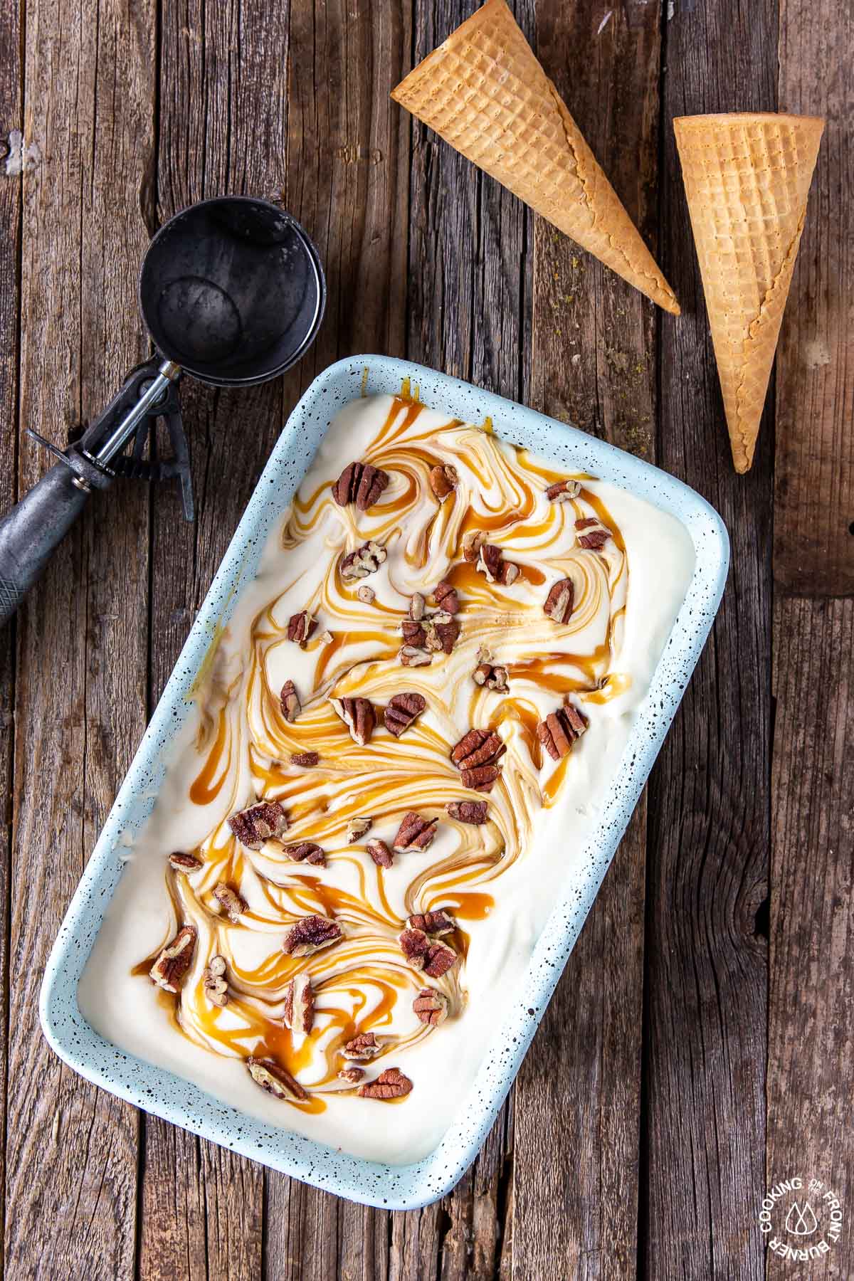 no churn bourbon pecan caramel ice cream in a loaf pan with a ice cream scoop next to it