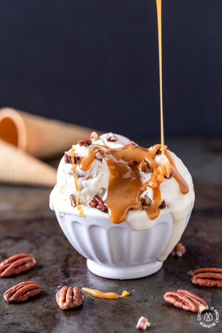 a bowl of no churn bourbon pecan caramel ice cream drizzled with more caramel sauce