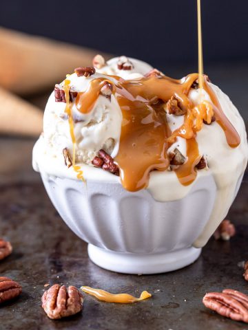 a bowl of no churn bourbon pecan caramel ice cream with caramel being poured on top