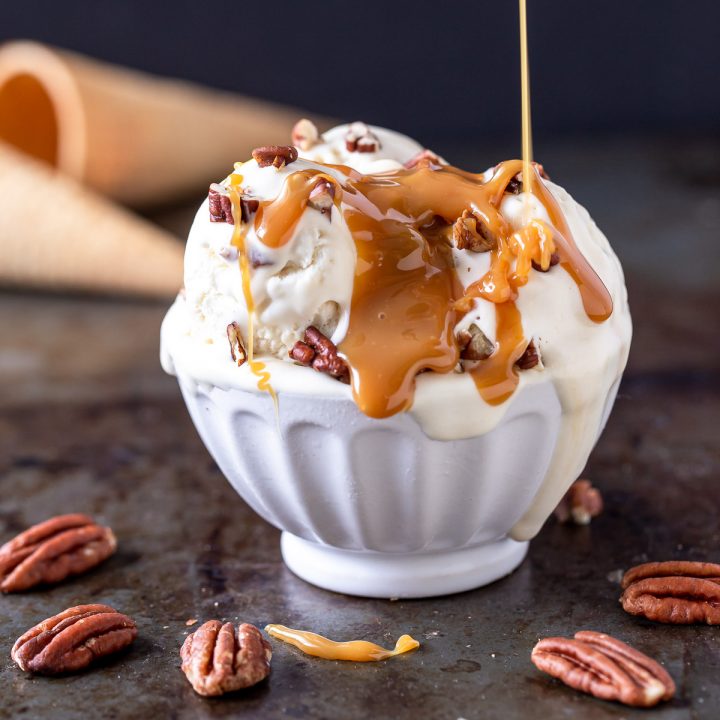 a bowl of no churn bourbon pecan caramel ice cream with caramel being poured on top