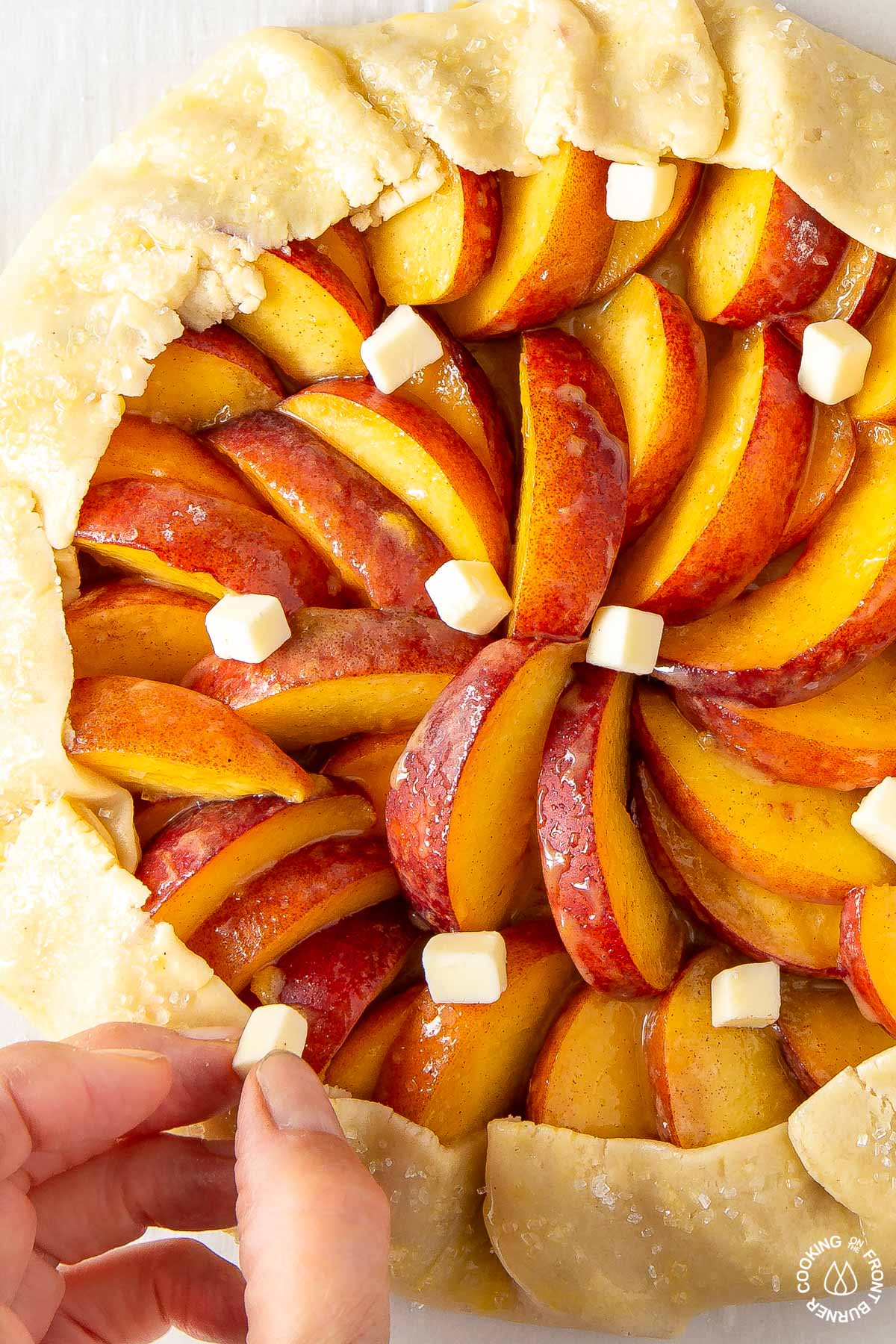 placing small pieces of butter on a unbaked peach galette