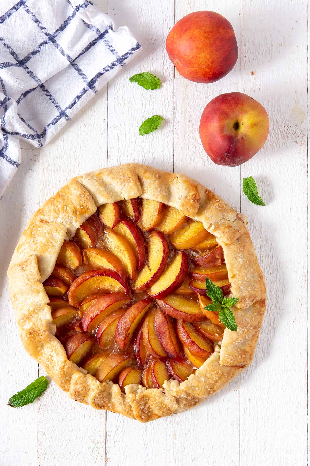 a peach galette on a board unsliced