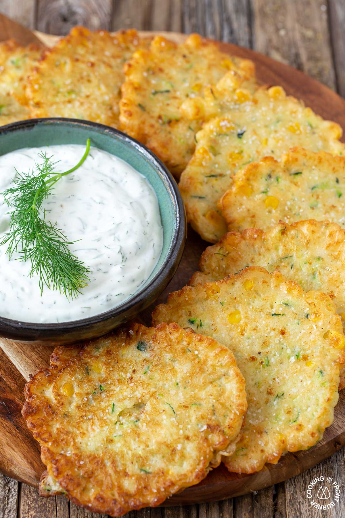 fried zucchini corn fritters on a board with a side of dill dip