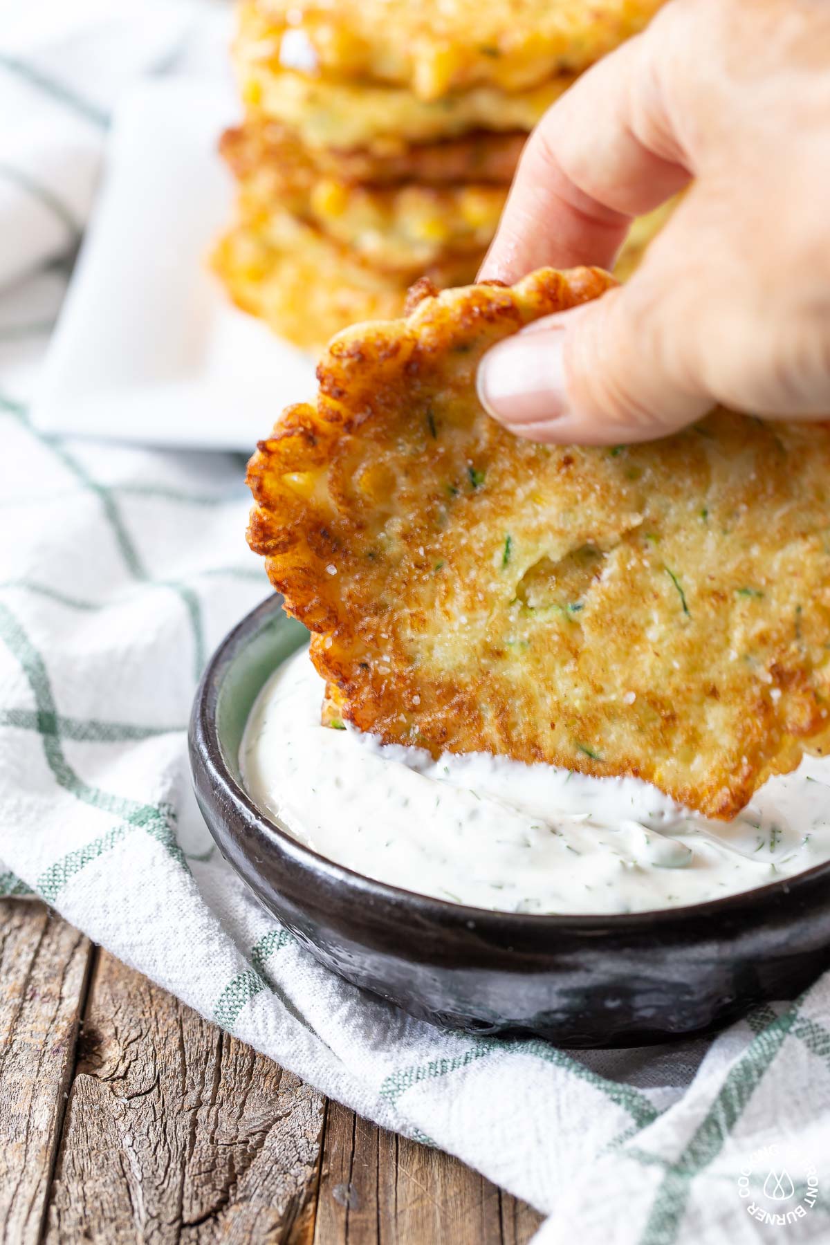 dipping a zucchini fritter into dill dip