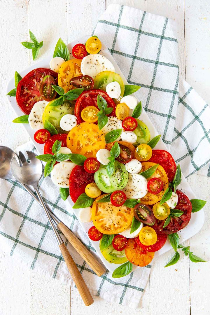 white platter, heirlooom tomatoes, mozzarella cheese, fresh basil arranged