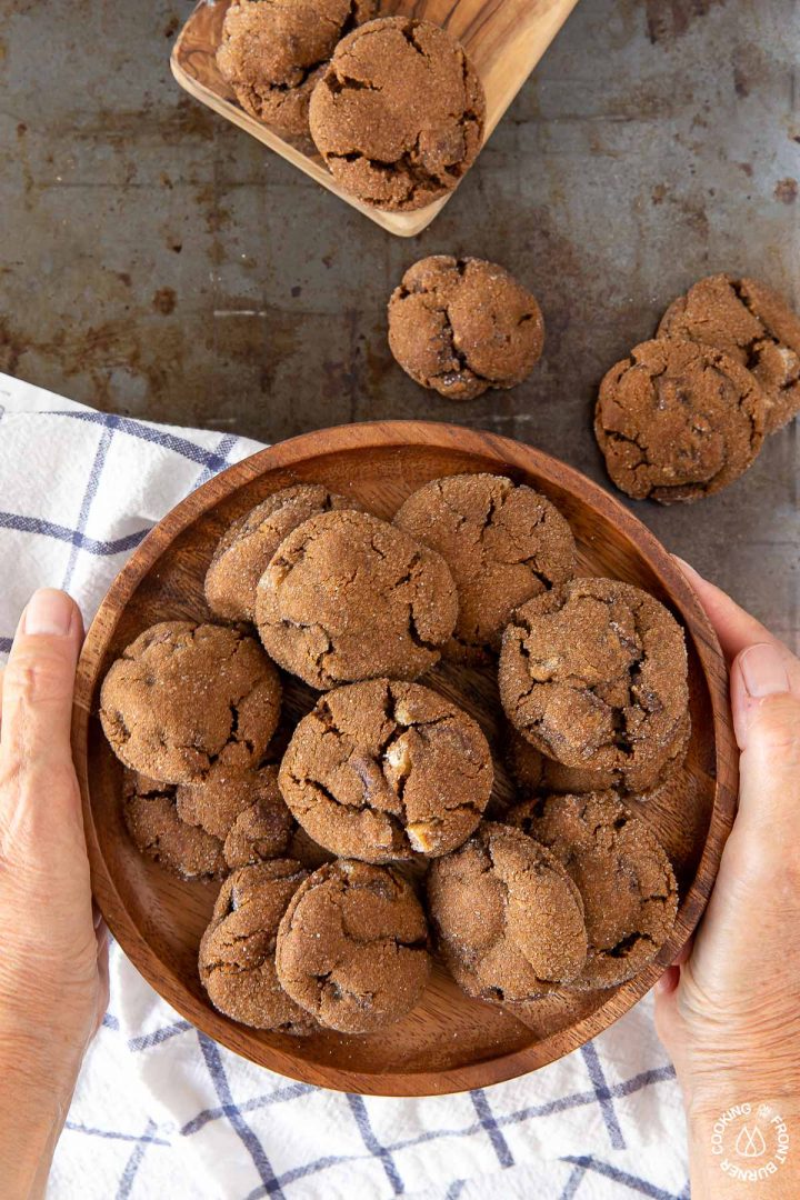 a plate of triple ginger chocolate cookies being held by 2 hands