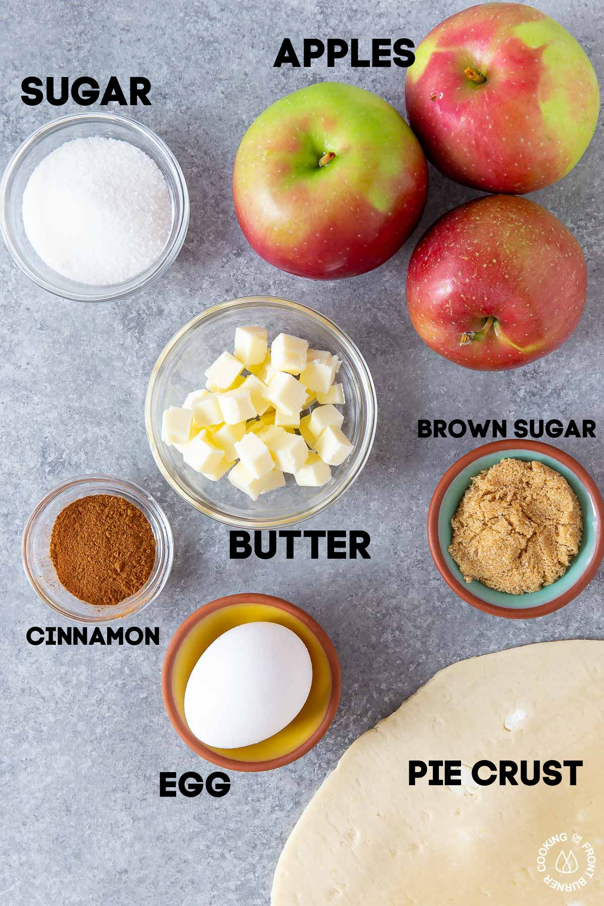 sugar, brown sugar, apples, butter, cinnamon, egg and pie crust on a board
