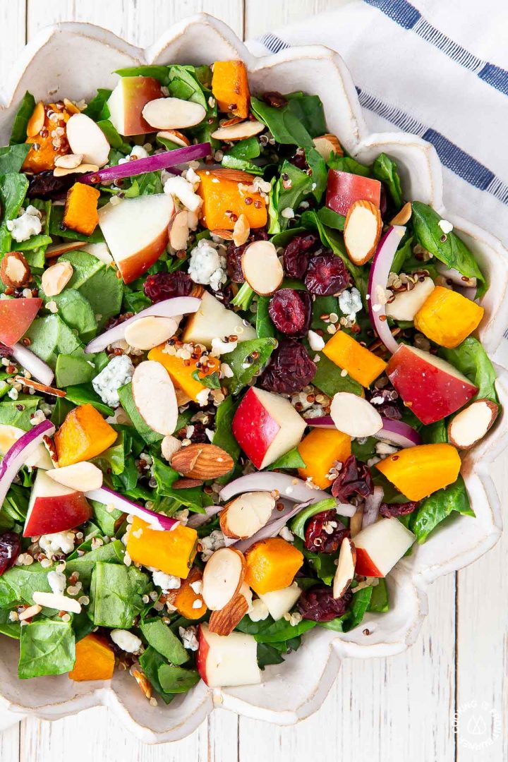 chopped spinach, almonds, blue cheese, butternut squash, apples, red onions in a bowl