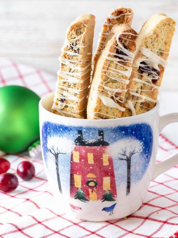 4 cranberry pistachio biscotti standing in a mug on a towel