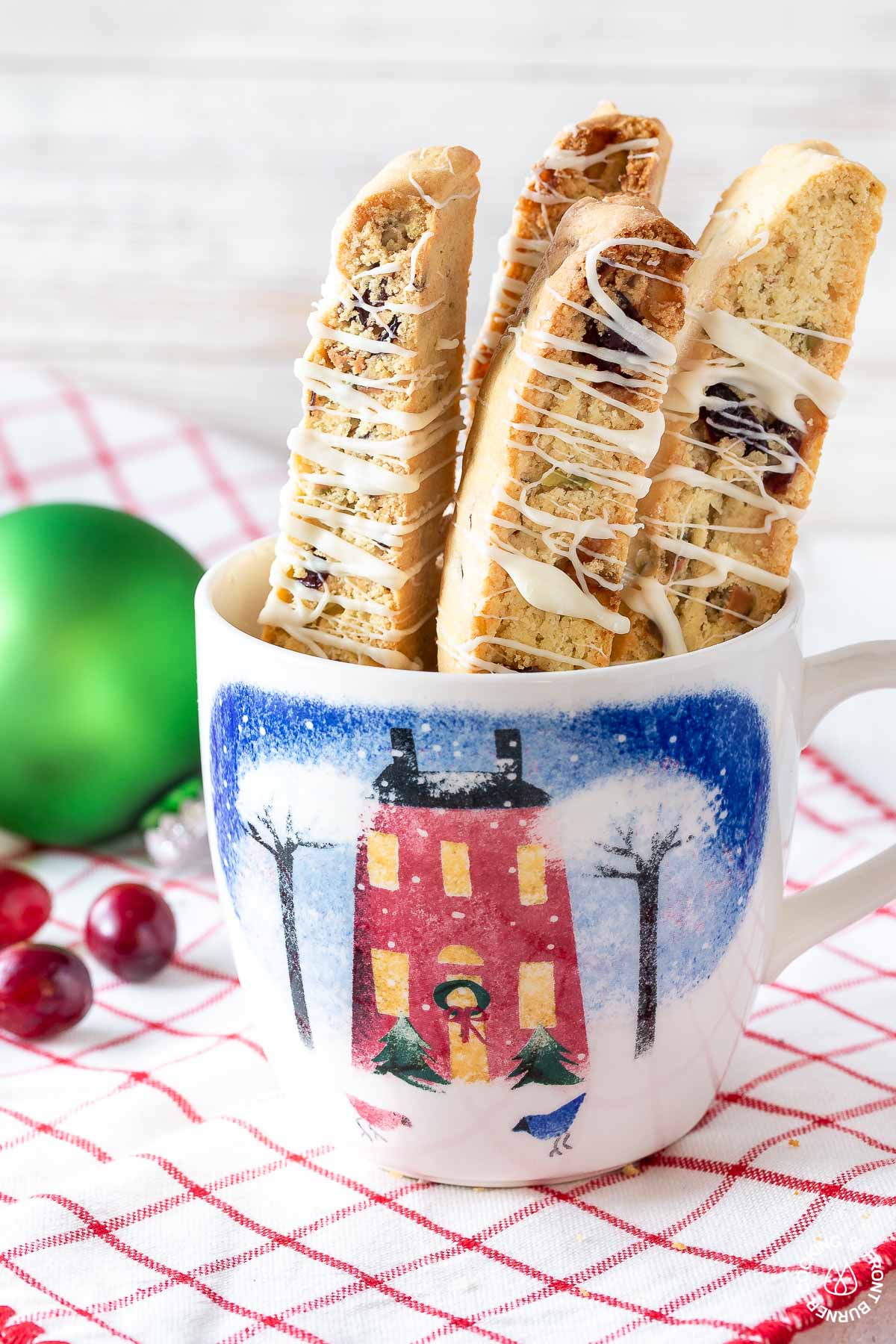 4 cranberry pistachio biscotti standing in a mug on a towel