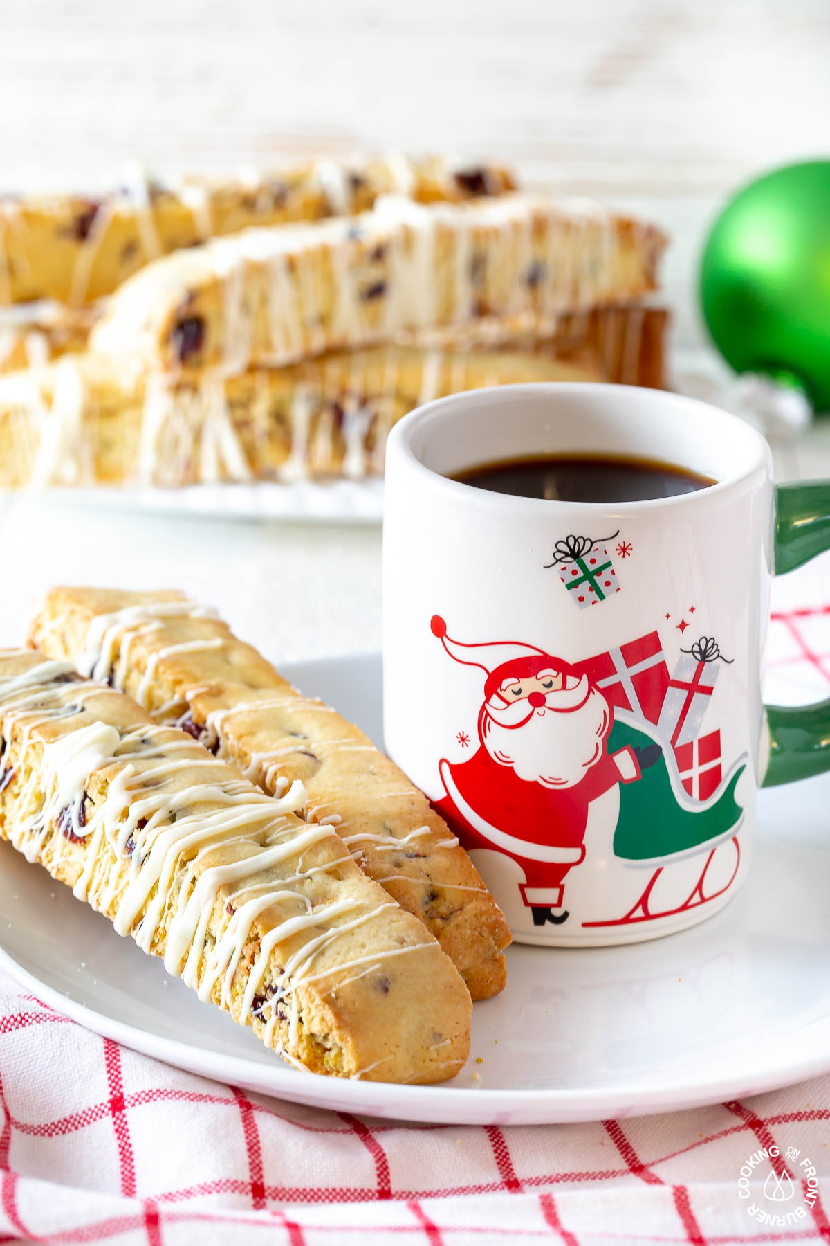 a cup of coffee with two cranberry pistachio biscotti on a plate