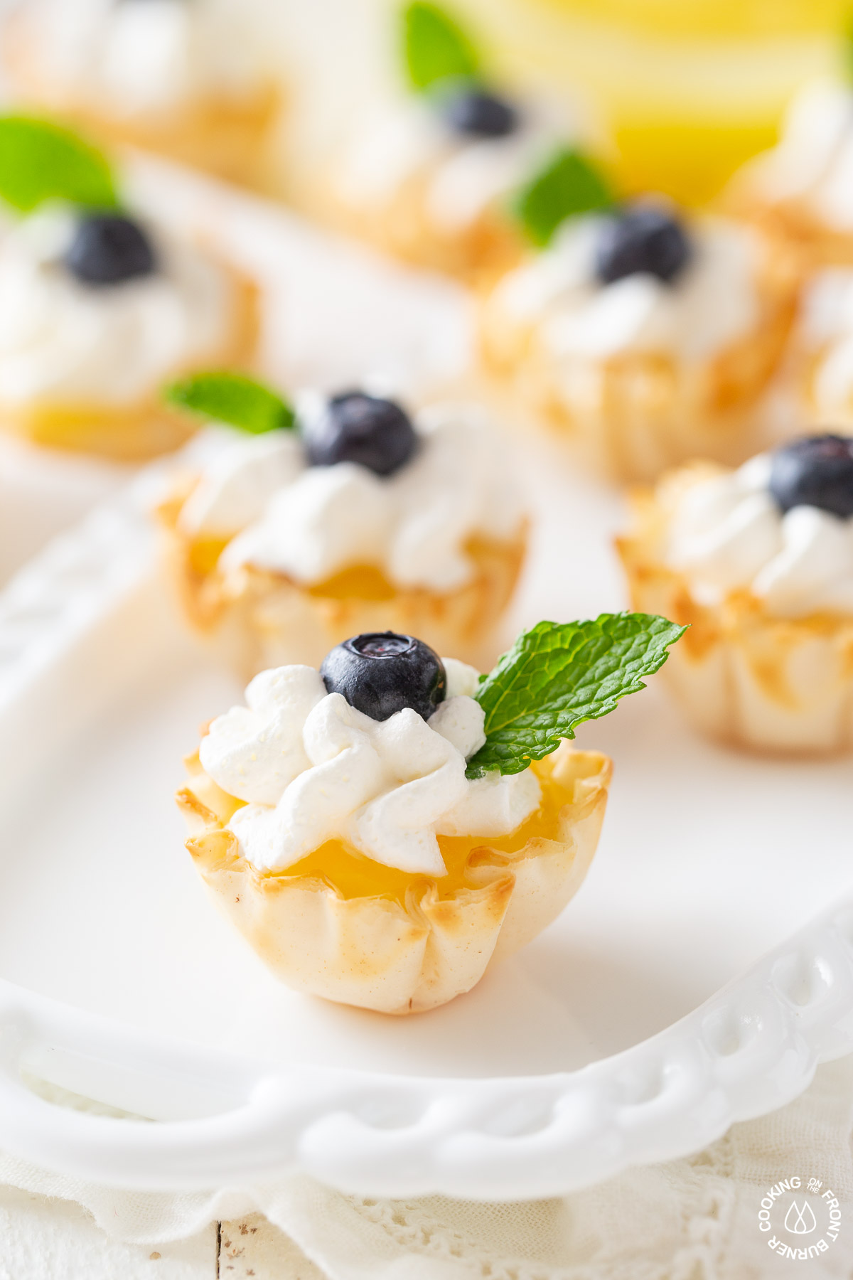 a phyllo cup with lemon curd topped with whipped cream and sprig mint