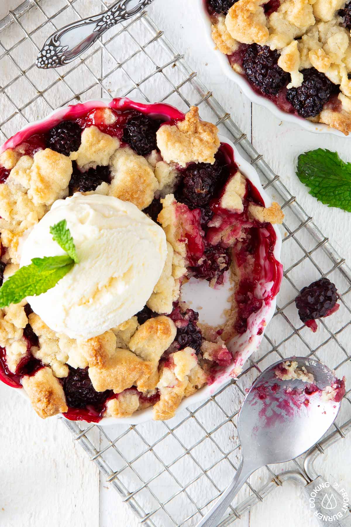 blackberry crumble in a white tart pan with vanilla ice cream on top