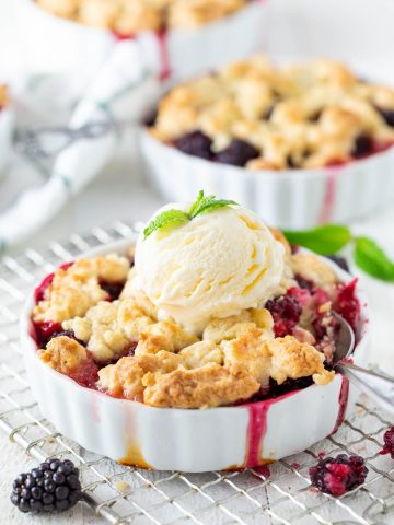 blackberry crumble in a white dish with a scoop of vanilla ice cream