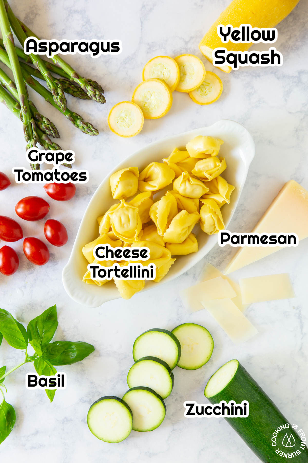 asparagus, grape tomatoes, tortellini, parmesan cheese, basil, squash on a board