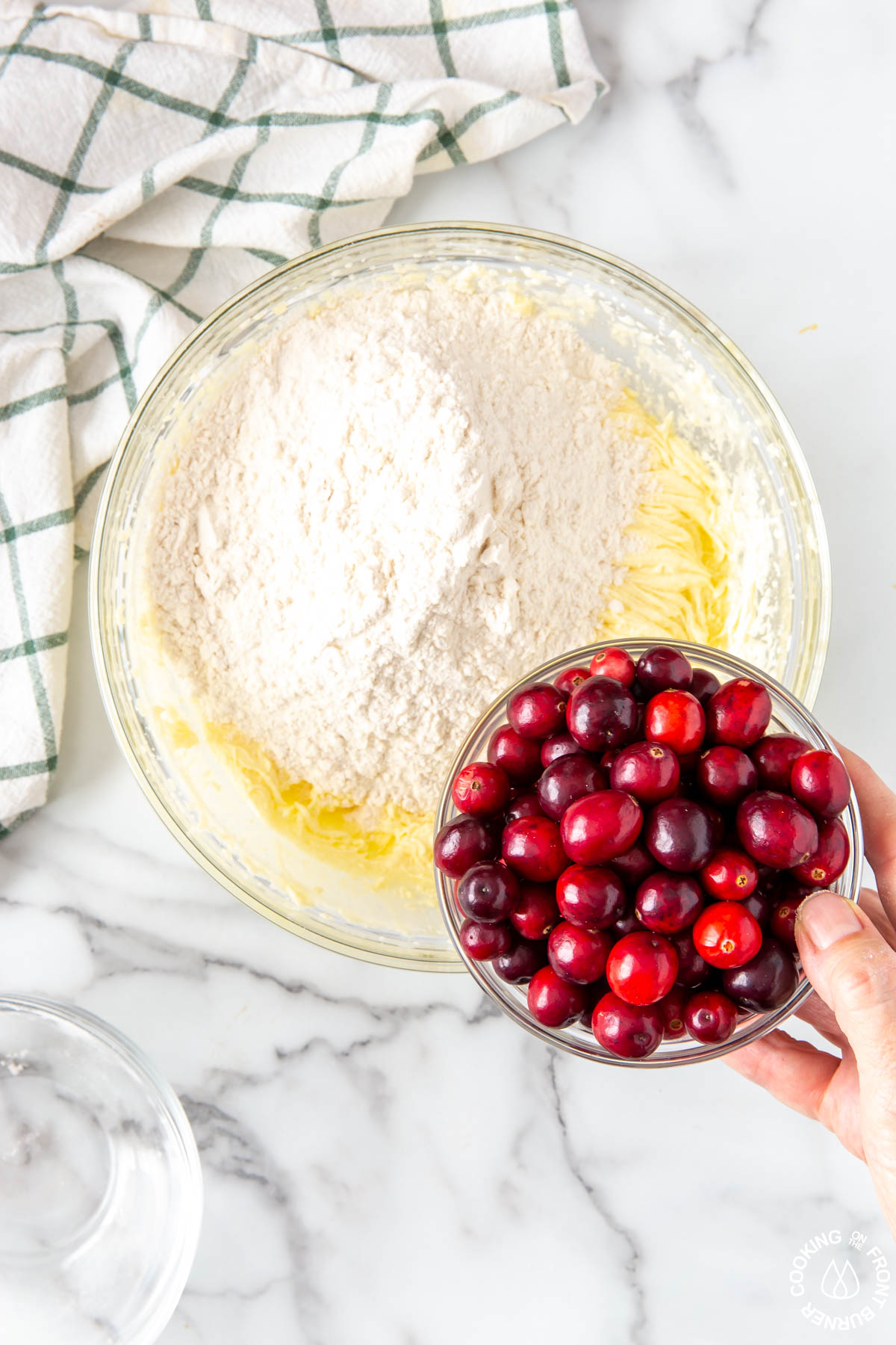 adding flour and cranberries to a creamed sugar mixture