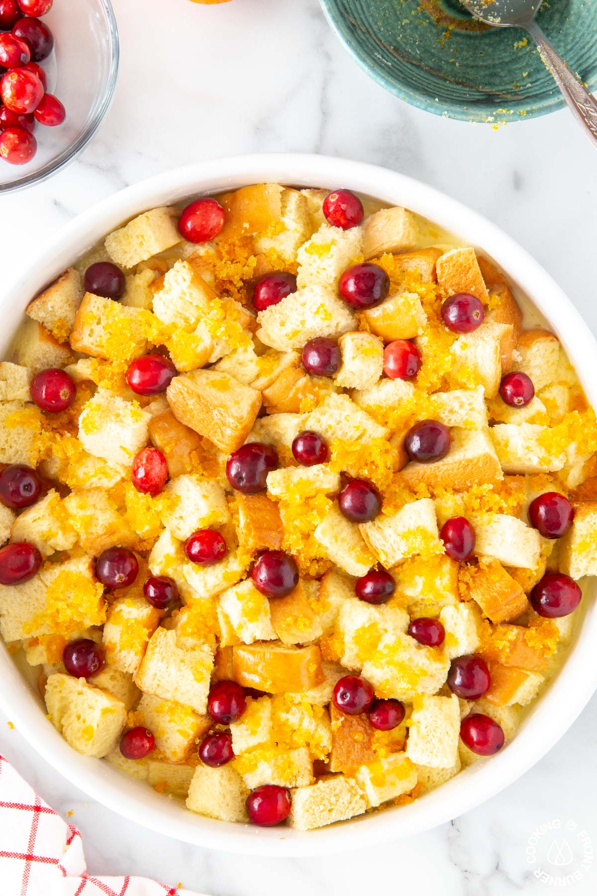orange cranberry french toast in a white baking dish topped with fresh cranberries