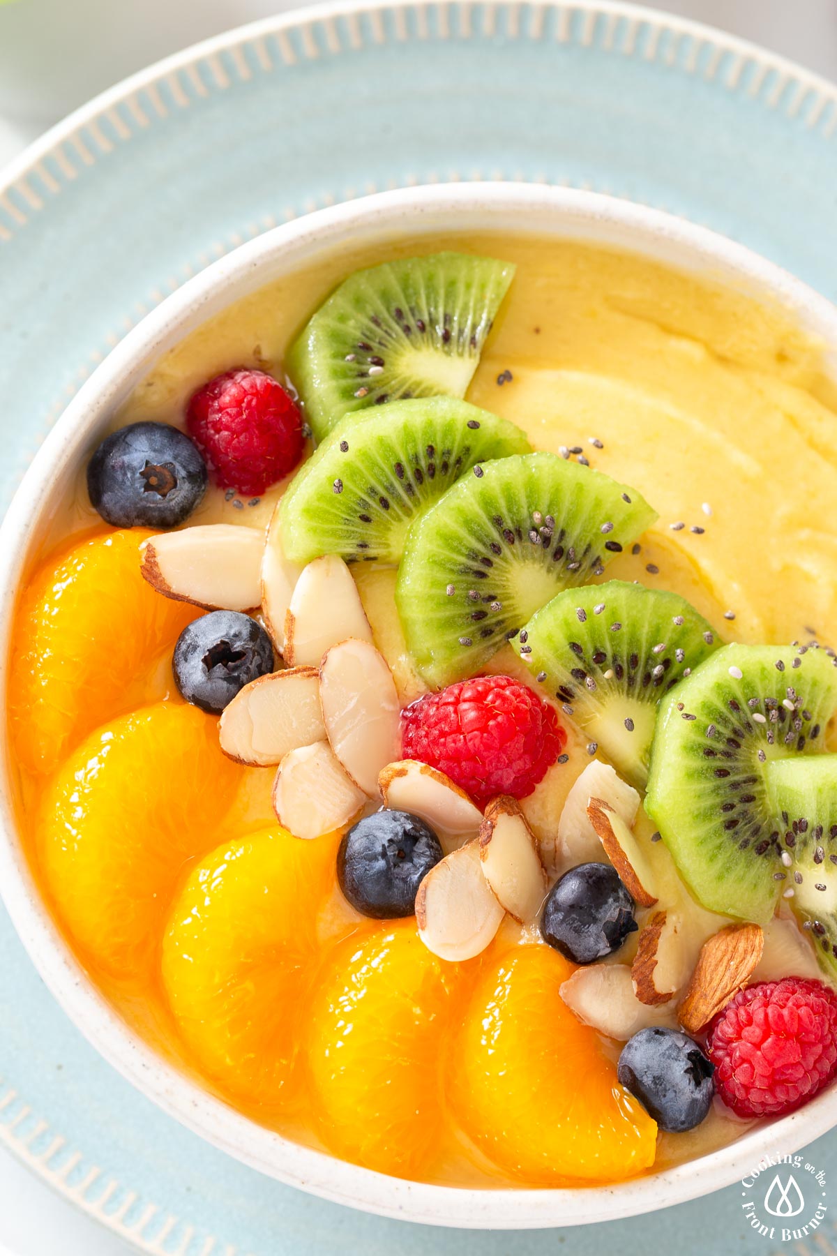 tropical smoothie in white bowl topped with oranges, blueberries, kiwi