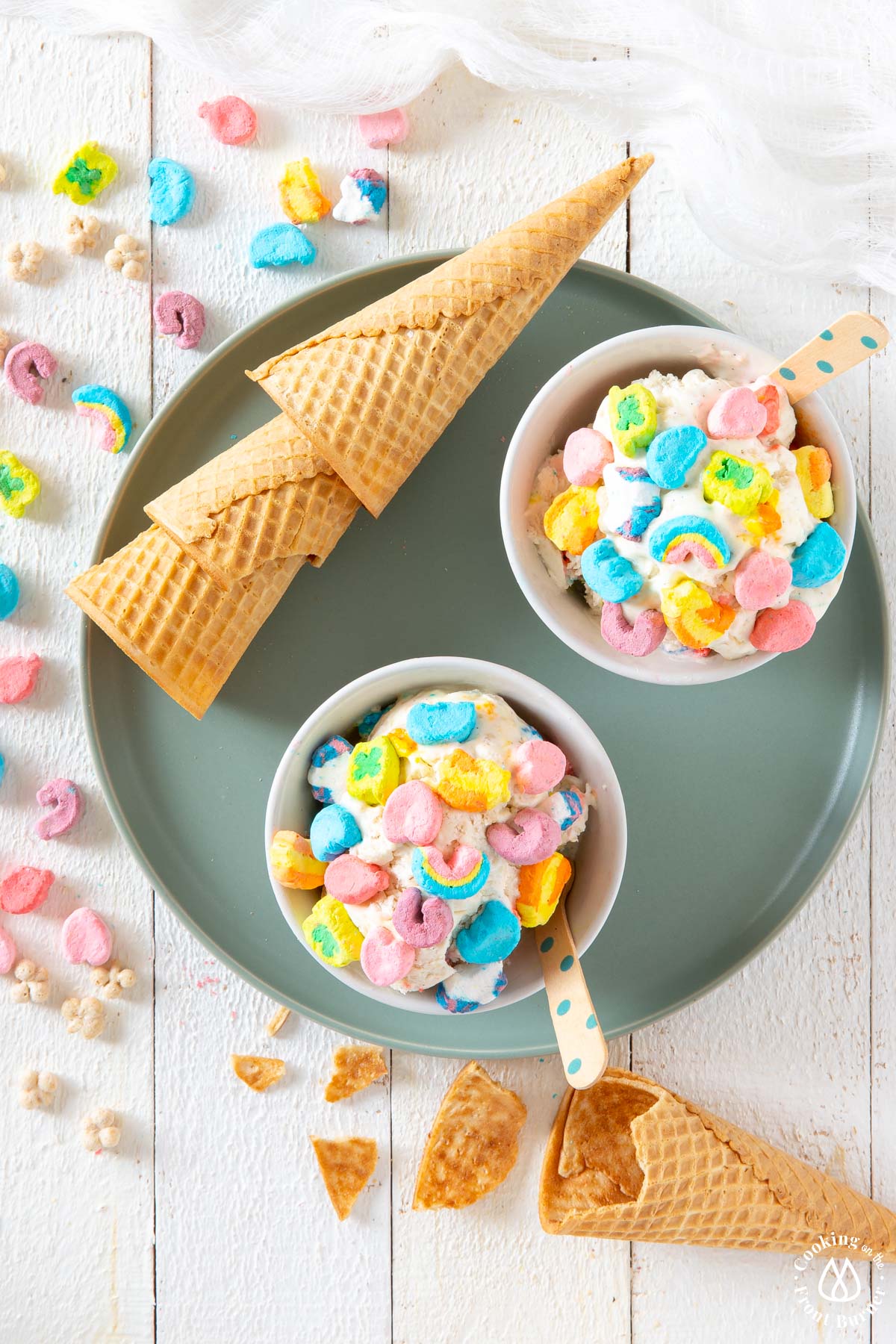 a green plate with 2 white bowls of lucky charm ice cream