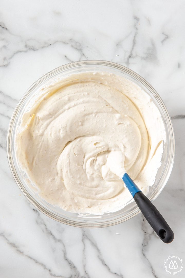 whipped cream mixture in a clear bowl with spatula