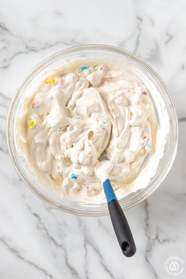 mixture of whipped cream and lucky charm marshmallows in a clear bowl