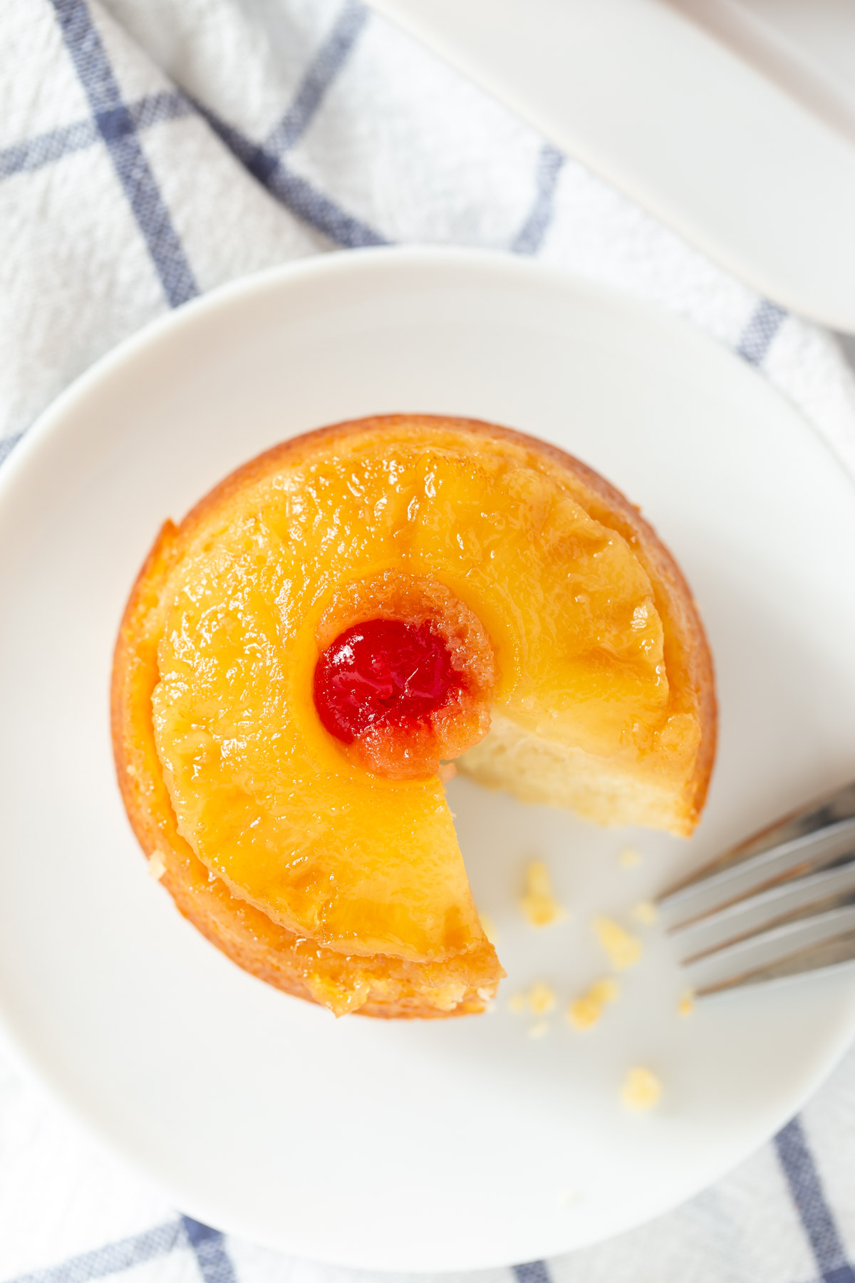 mini pineapple upside down cake with a slice cut out on a white plate