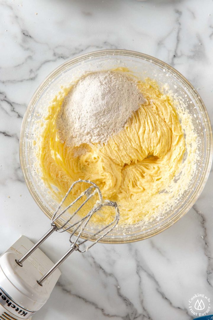 flour being adding to creamed butter sugar mixture