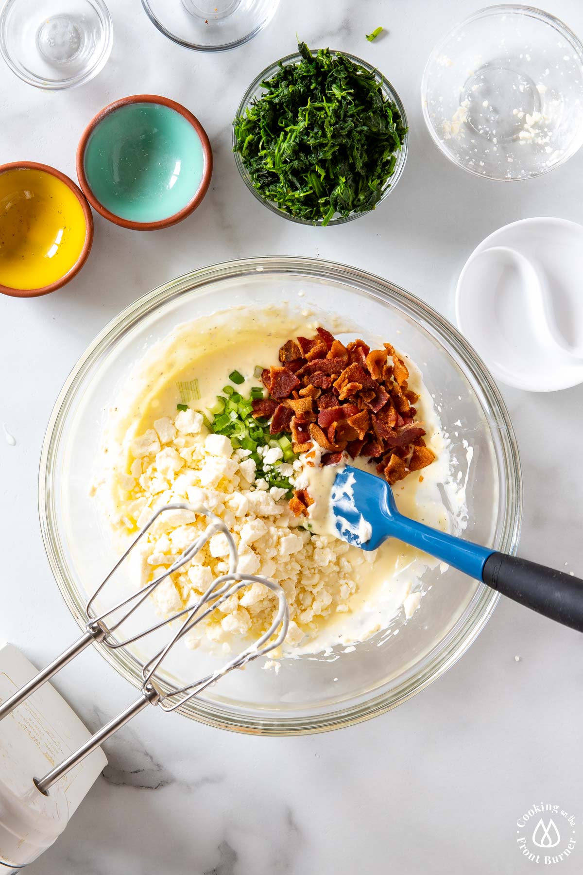 a cream mixture with bacon, feta and scallions being folded in