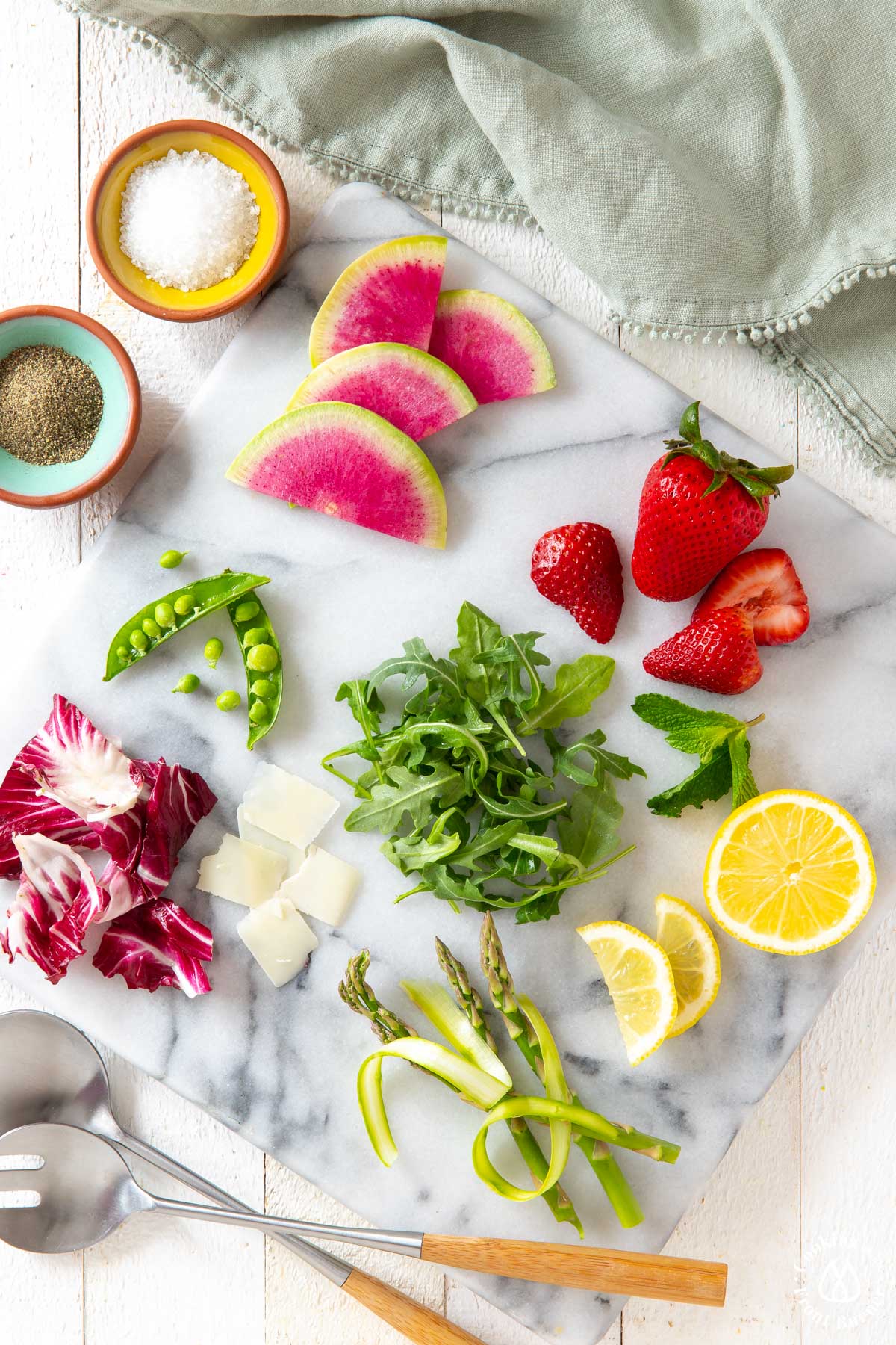 watermelon radishes, arugula, strawberries on a marble slate with other veggies