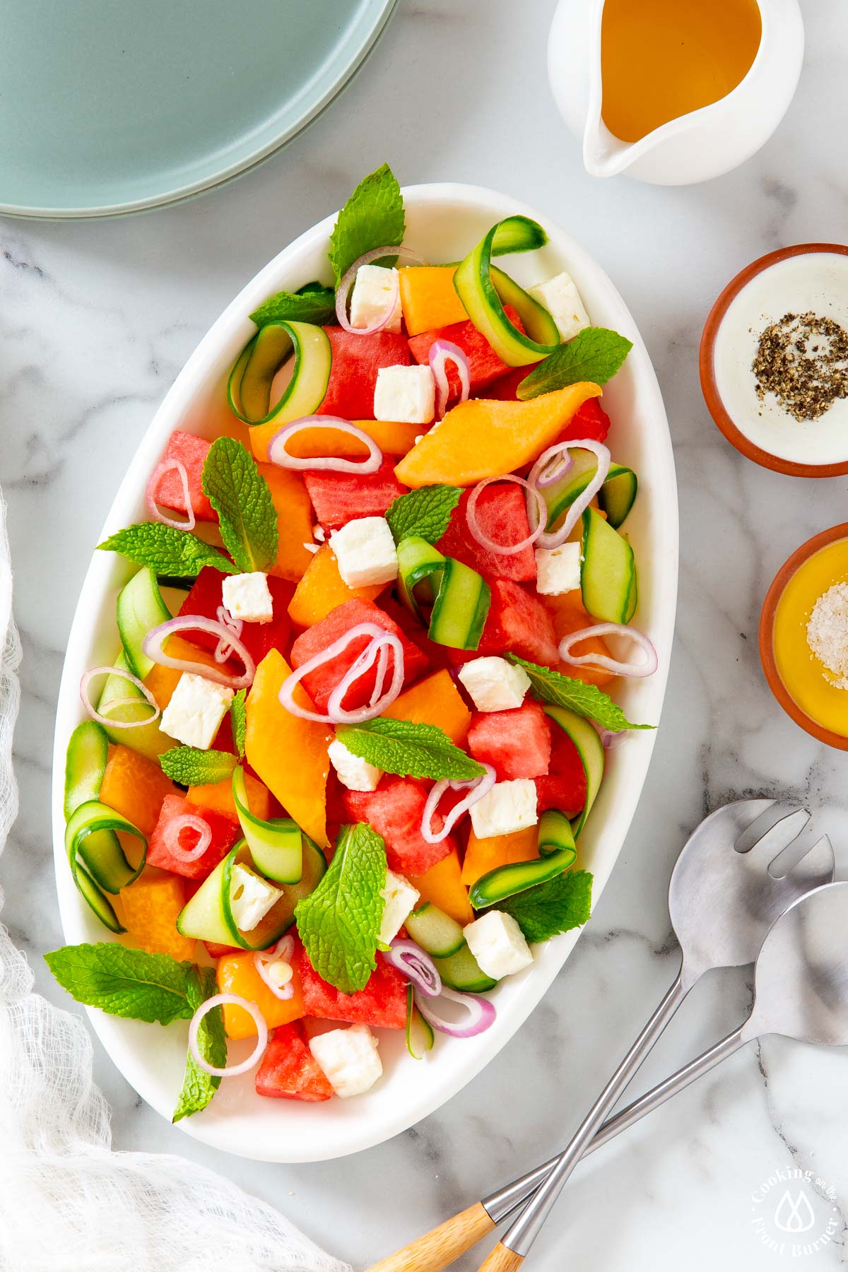 white platter with fresh melon, feta, cucumber ribbons