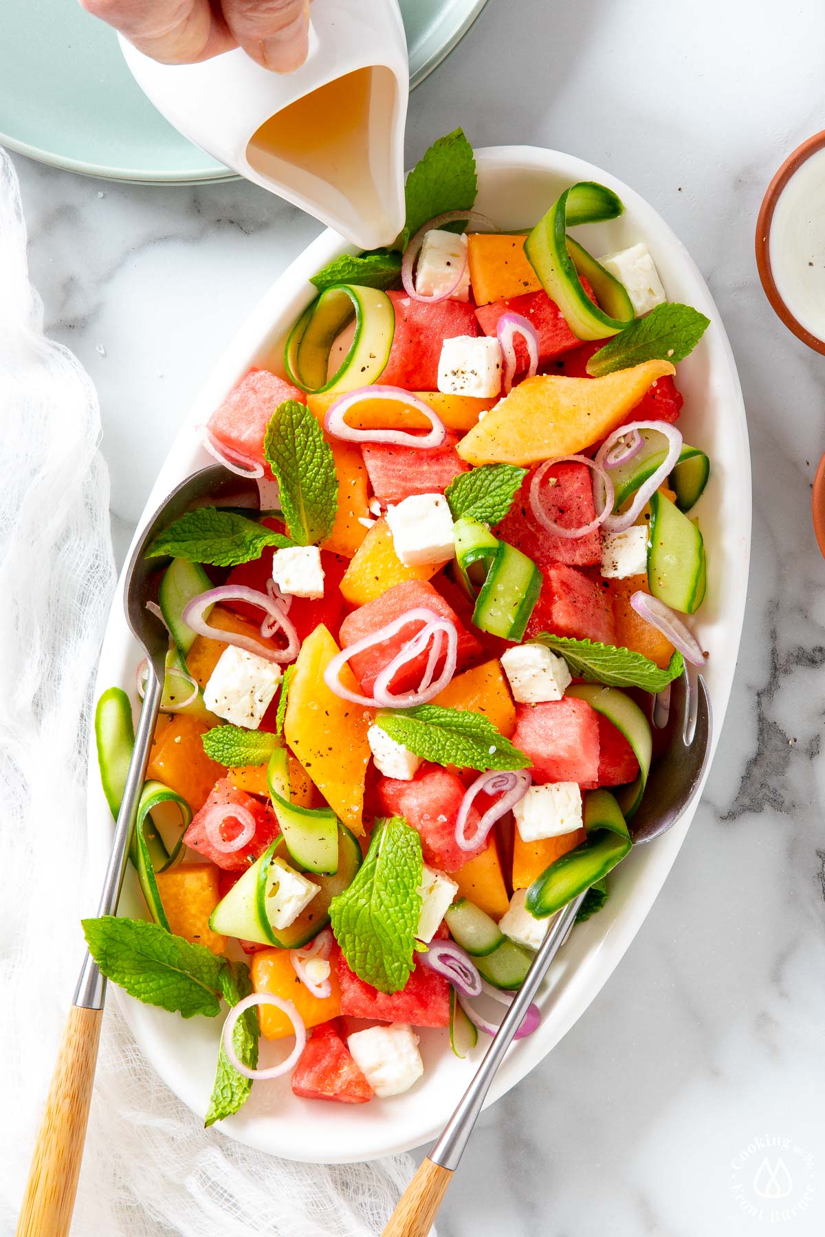 white plate with chunks of watermelon, cantaloupe, feta, mint