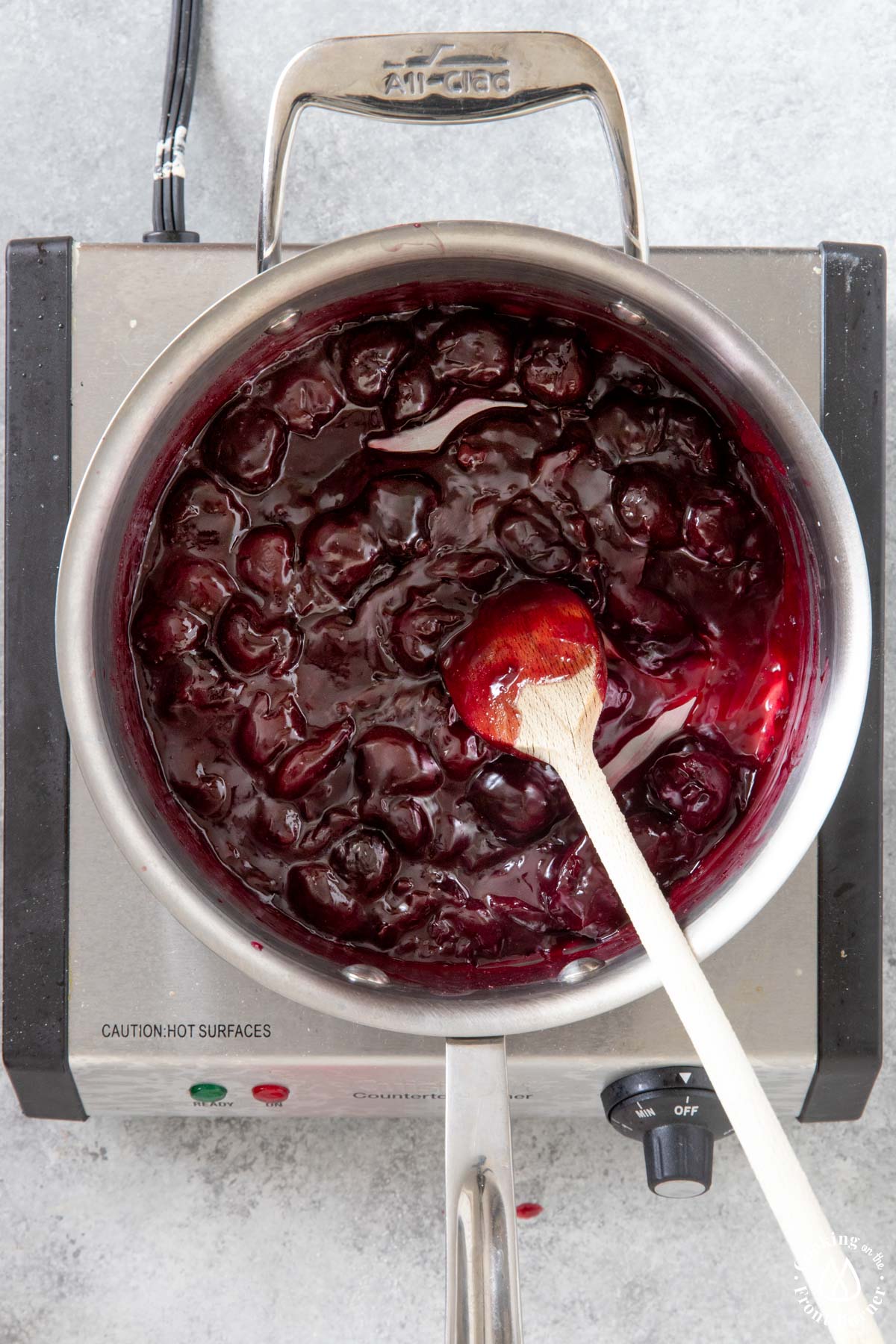 homemade cherry filling in a saucepan with a spoon